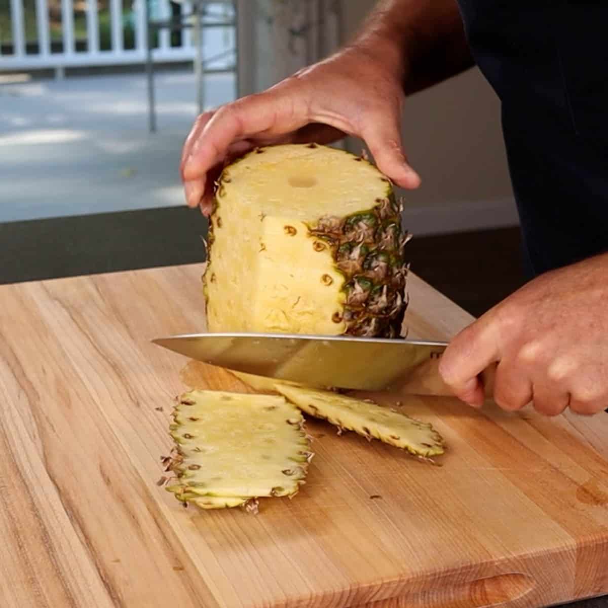 Cutting the skin off from a pineapple with a chef knife
