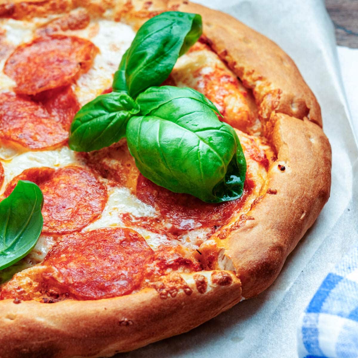 Freshly cooked pepperoni pizza with fresh basil leaves.