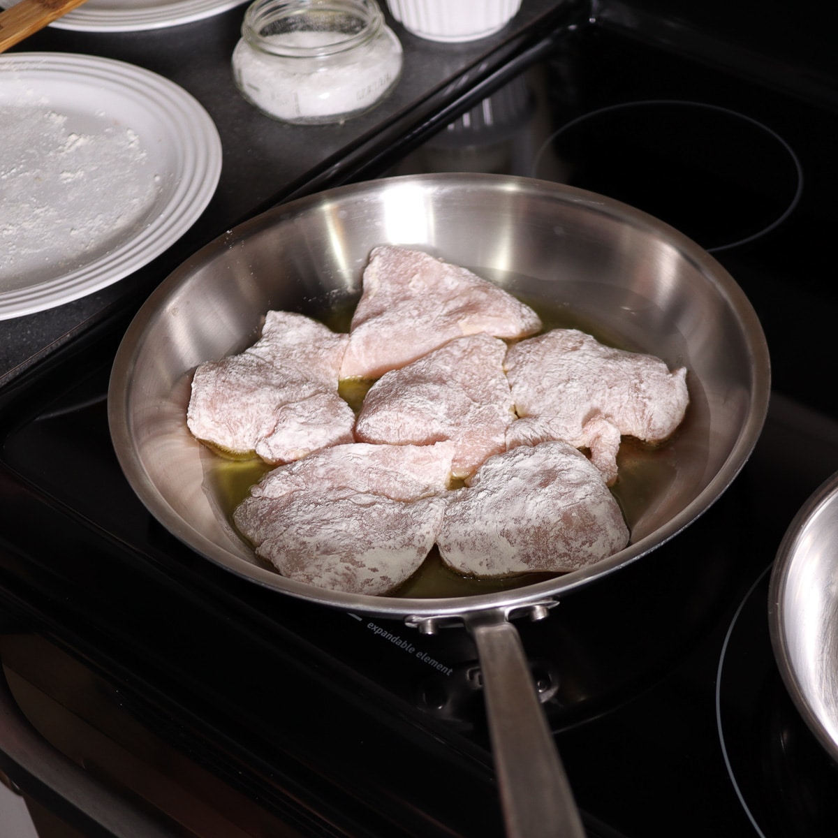 chicken that is floured added to preheated pan with oil