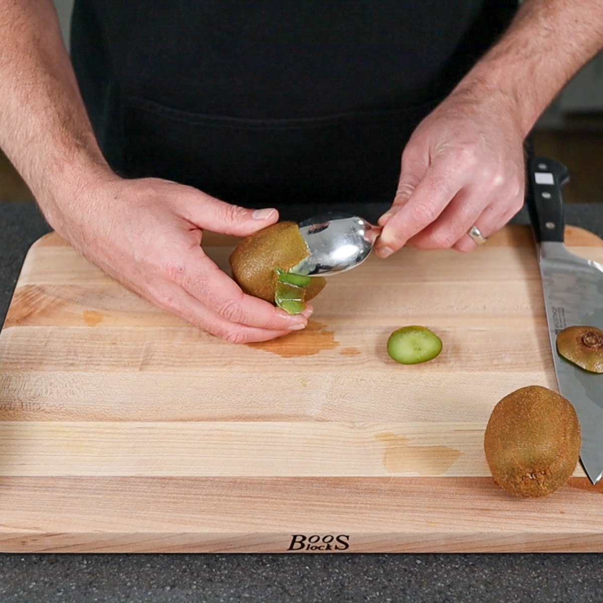 kiwi fruit being peeled with a spoon
