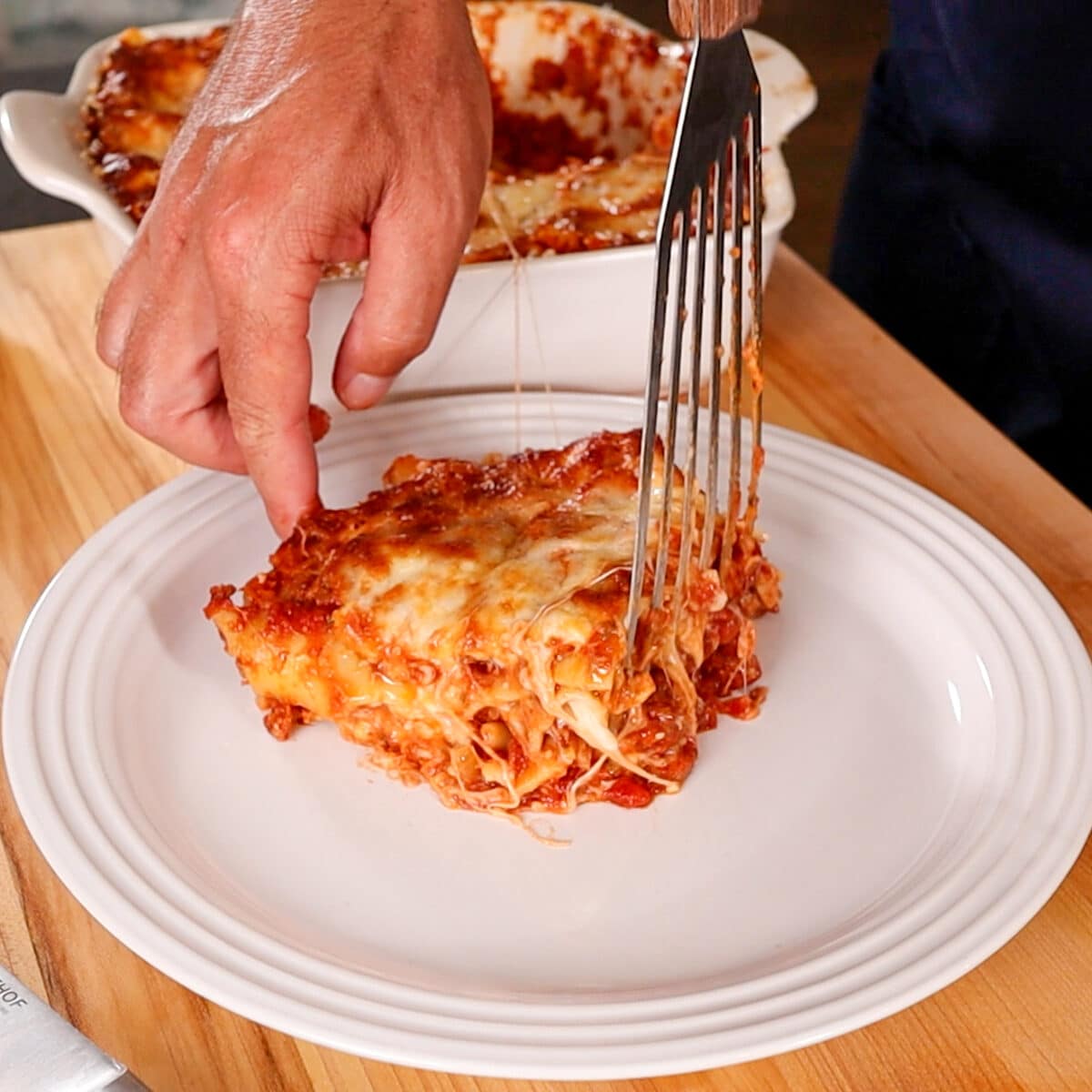 adding a slice of lasagna to a plate