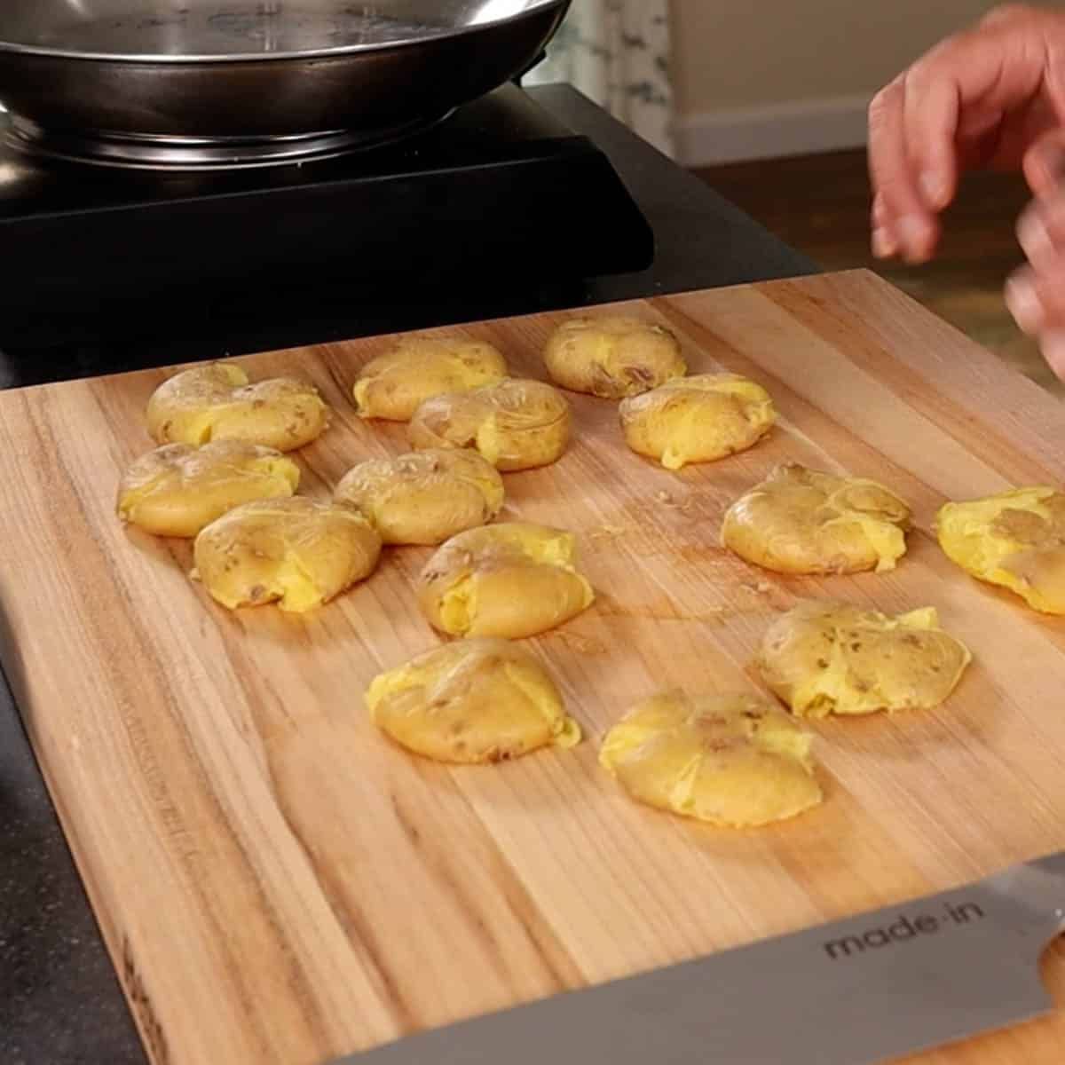 Smushed baby Yukon potatoes on a cutting board