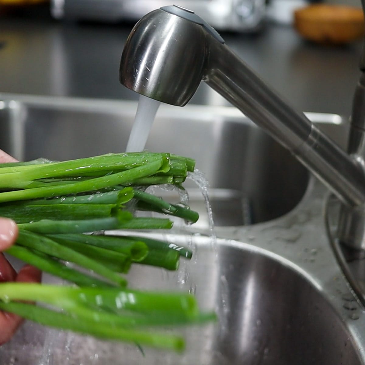 Washing green onions in the sink with cold water
