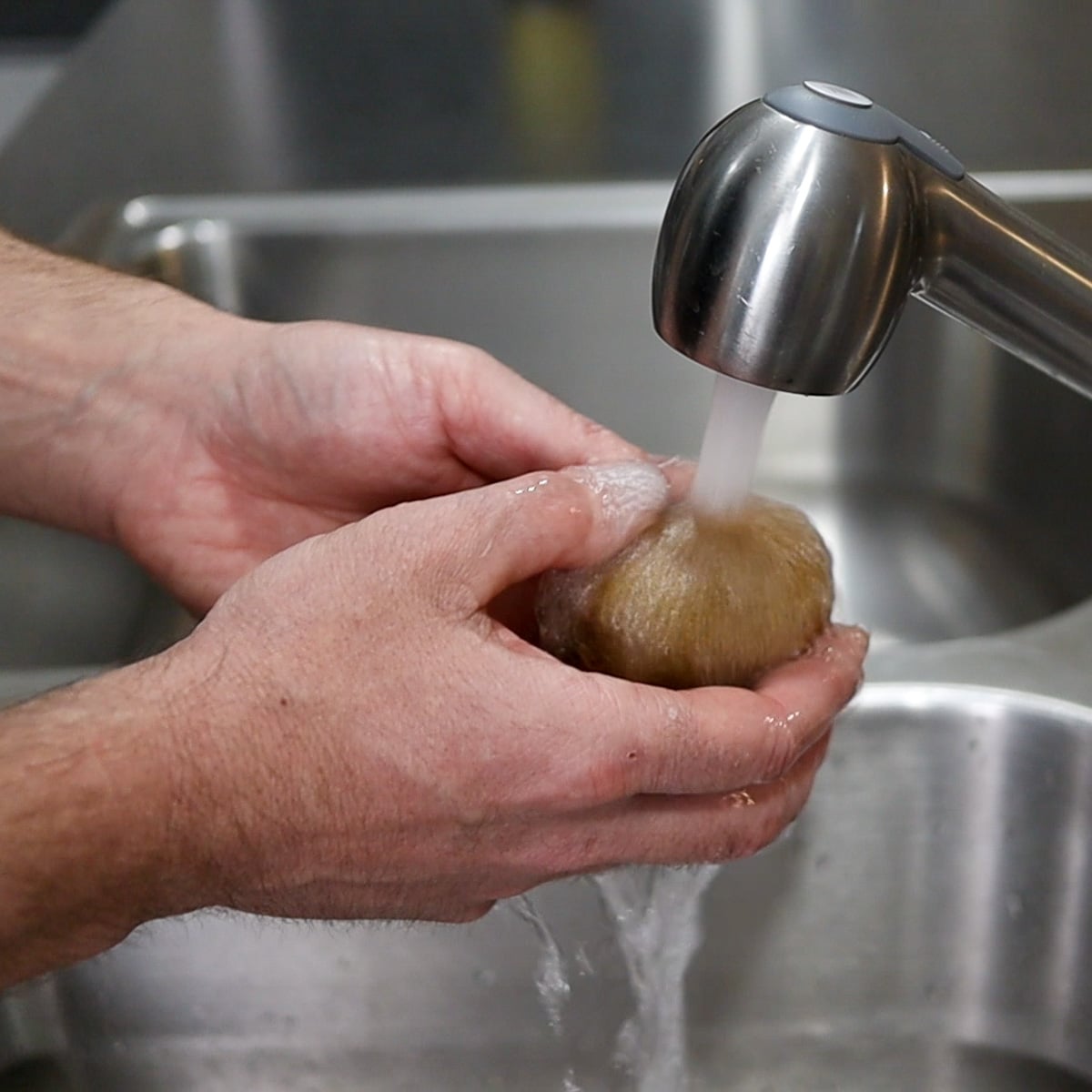 Washing a kiwi fruit under running water
