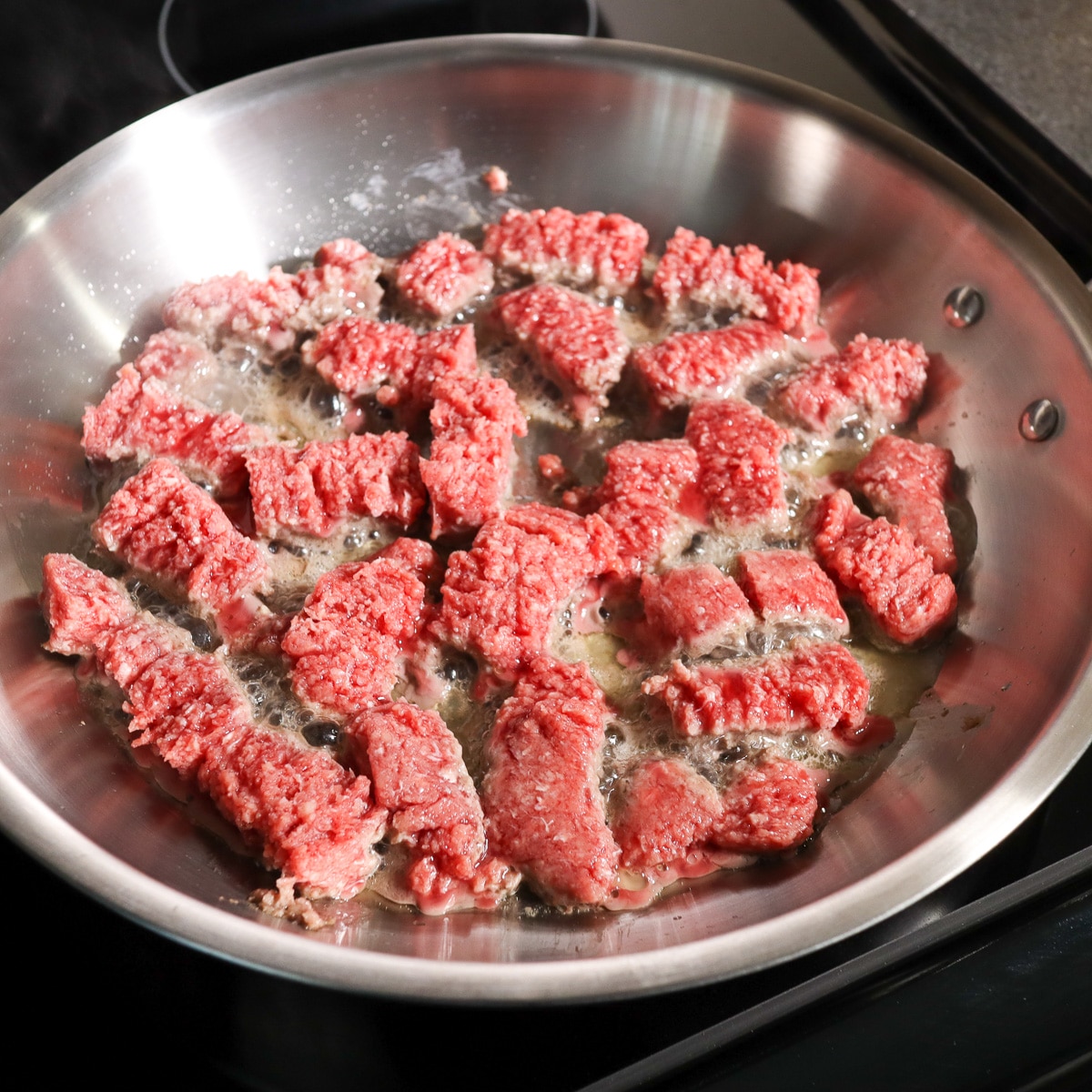 ground beef just added to a pan to cook
