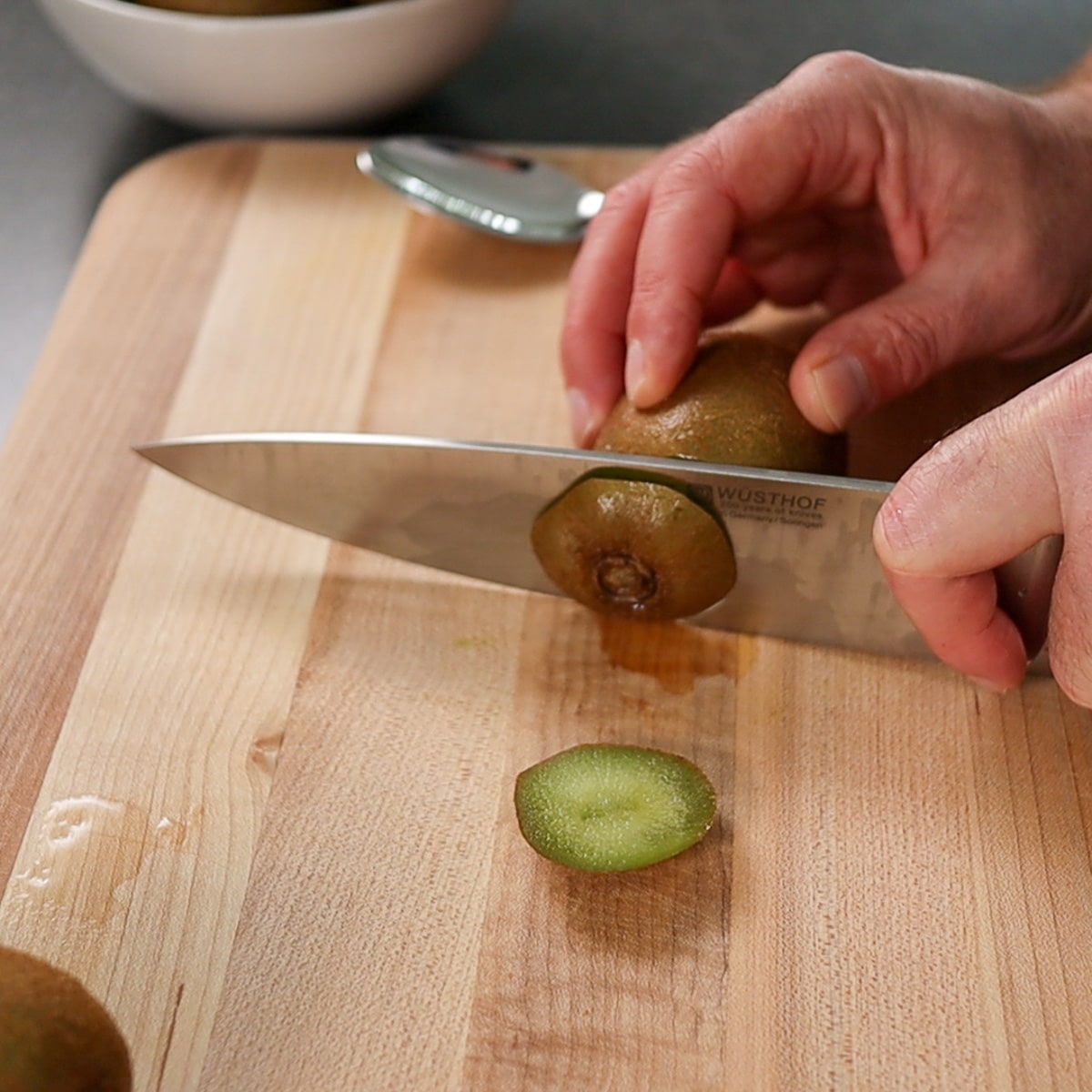 a knife cutting the ends of a kiwi