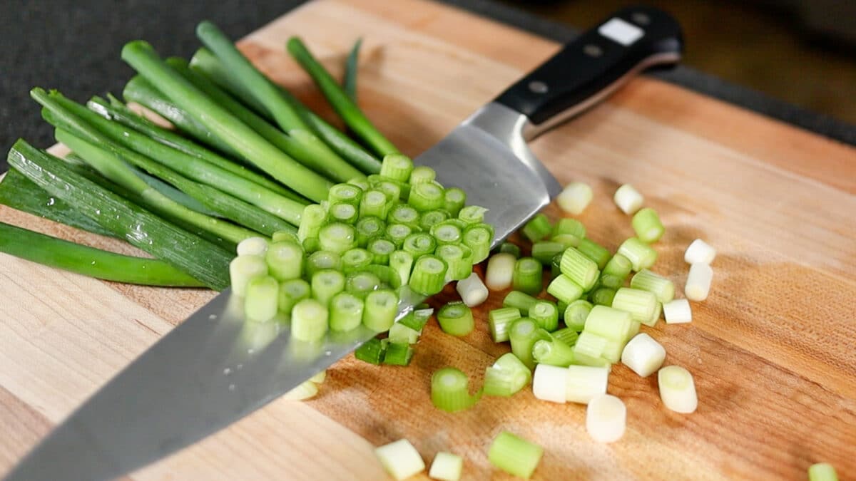 green onions being cut on a cutting board