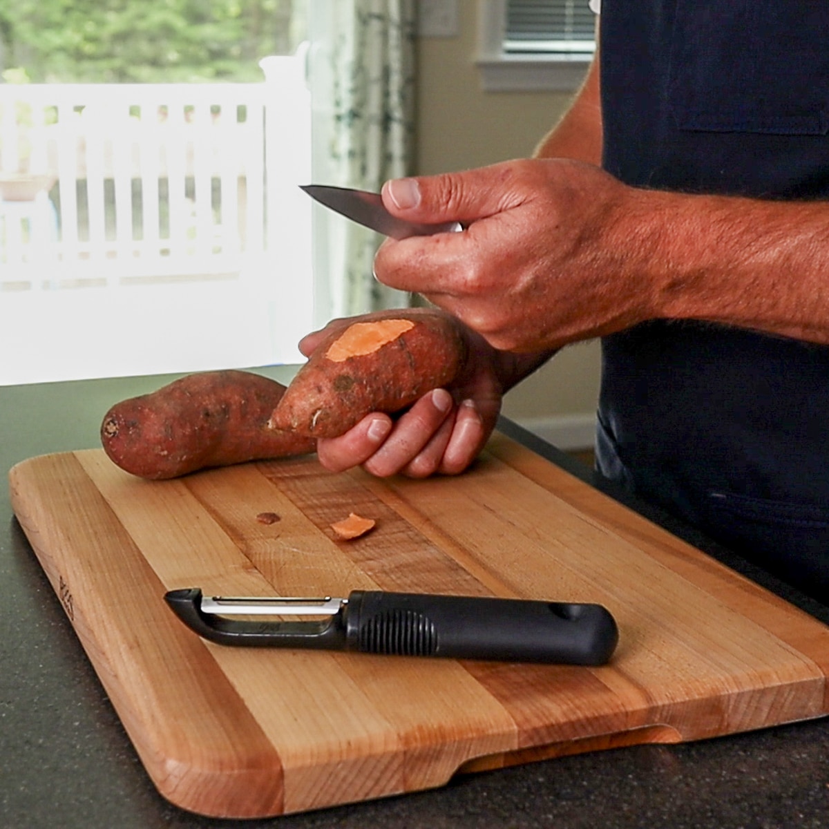 using a pairing knife and a peeler to peel a potato.