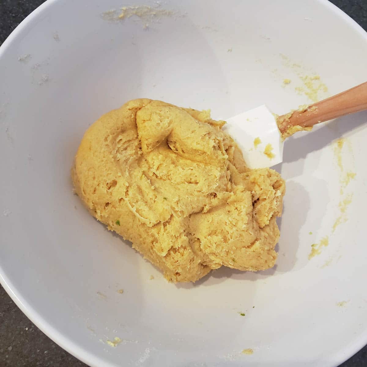 Scone dough in a white bowl with a rubber spatula.